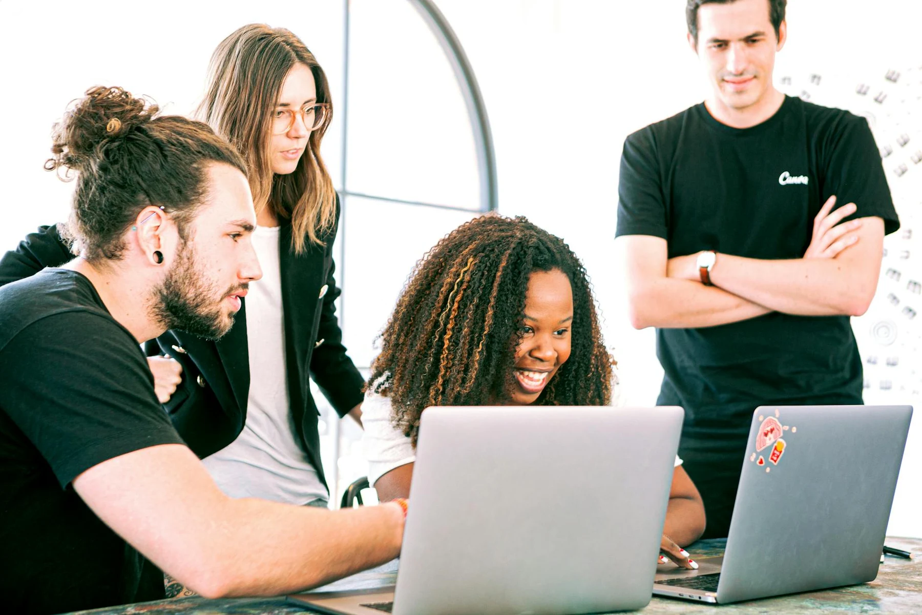 A diverse group of young professionals collaborating enthusiastically in a bright, modern workspace.