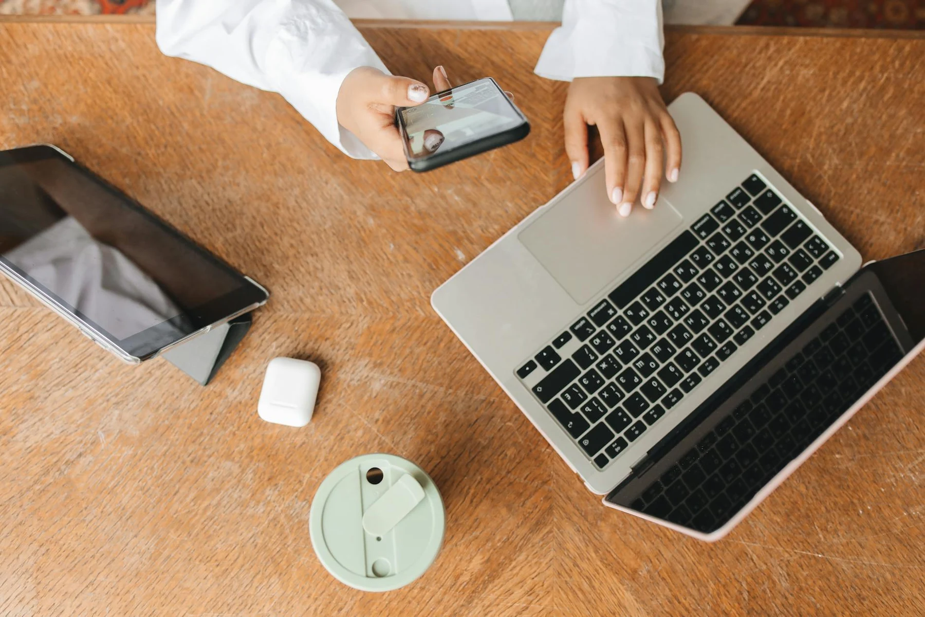 Top view of a workspace featuring a laptop, tablet, phone, and beverage. Perfect for remote work context.